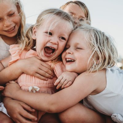 Close up of toddler laughing surrounded by young sisters