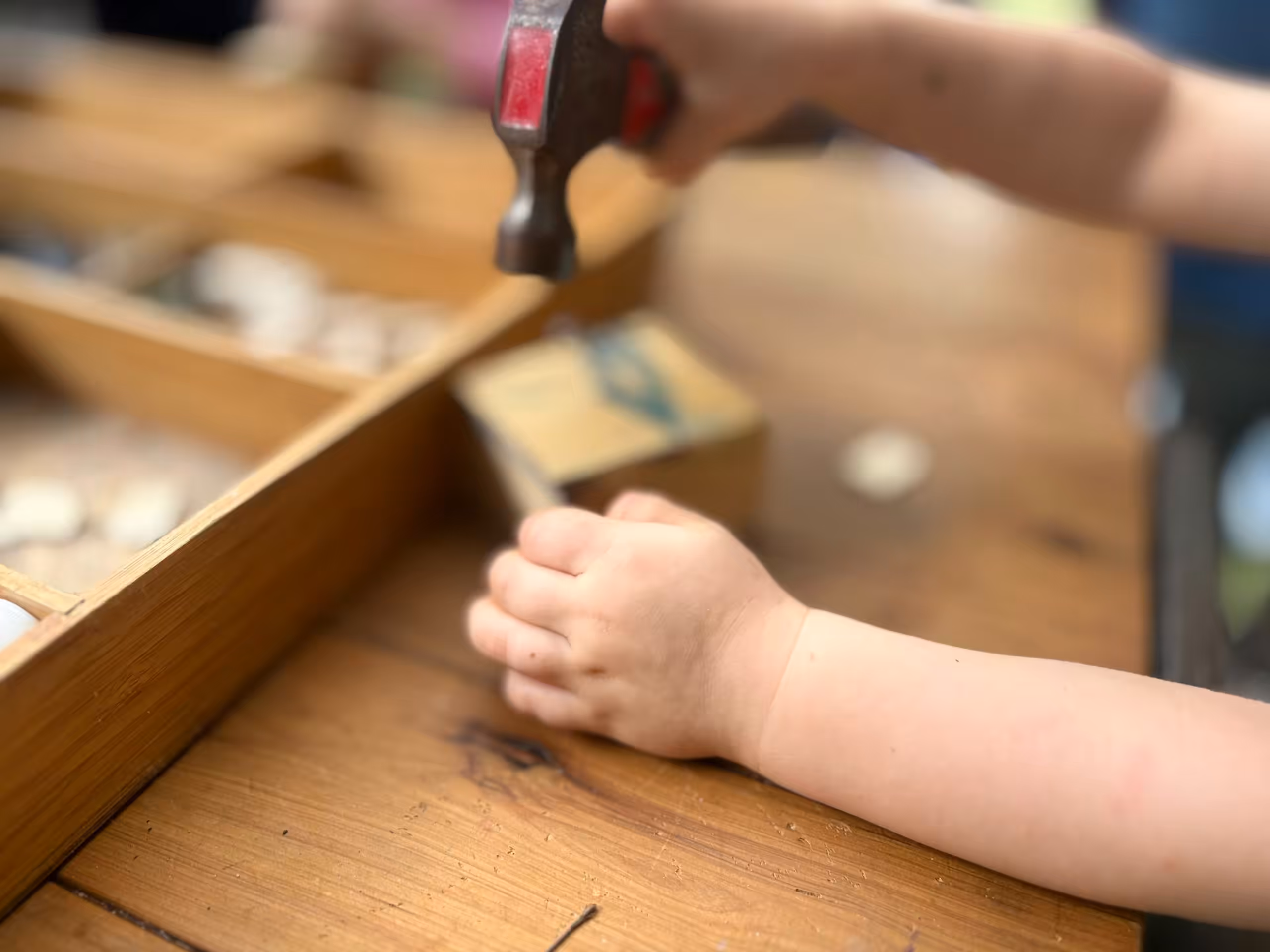 Kinderhände hämmern an einem Holztisch